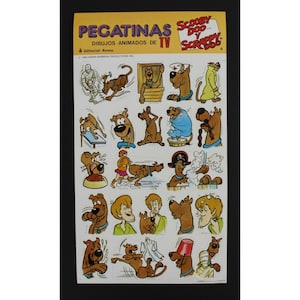 May include: A sheet of stickers featuring Scooby Doo and Scrappy Doo in various poses. The stickers are from the Hanna-Barbera Productions, Inc. cartoon series. The text on the sheet reads "PEGATINAS SCOOBY DOO Y SCRAPPY 4 DIBUJOS ANIMADOS DE TV Editorial Roma 1985 HANNA BARBERA PRODUCTIONS INC."