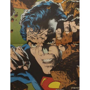 May include: A close-up of Superman's face, with a determined expression, as he breaks through a wall of rocks. His blue suit and red cape are visible in the background.