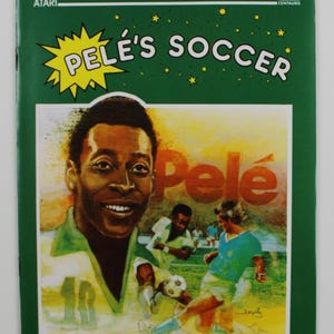 Könnte beinhalten: Eine grüne Atari-Spielbox mit einer gelben und weißen Illustration des Fußballspielers Pelé. Die Box trägt den Text "Pelé's Soccer" in weißen Buchstaben auf gelbem Hintergrund. Die Box zeigt auch ein kleineres Bild von Pelé mit dem Text "Pelé" in weißen Buchstaben auf gelbem Hintergrund.