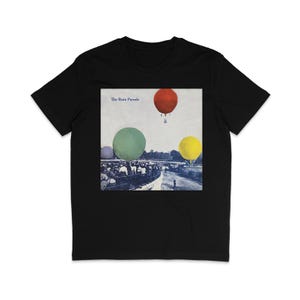 Puede incluir: Camiseta negra con un gráfico de tres globos aerostáticos coloridos y el texto "The Rain Parade" sobre un fondo blanco.
