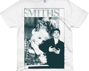 May include: White t-shirt featuring a black and white image of a band called "The Smiths". The image shows two men, one with his head down and the other looking at the camera. The text "The Smiths" is printed in a large, bold font at the top of the image.