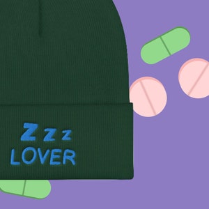 May include: A dark green beanie with the text "ZZZ LOVER" embroidered in blue on the front.