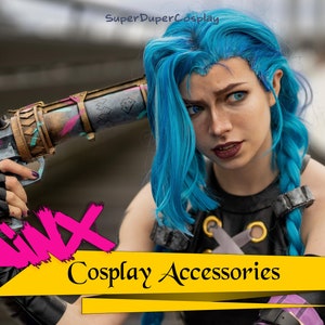May include: A woman cosplaying as Jinx from the video game League of Legends. She is holding a prop gun and wearing a blue wig, black leather gloves, and a black and grey top. The image has the text "Jinx Cosplay Accessories" on a yellow background.