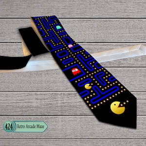 Könnte beinhalten: Schwarze Krawatte mit einem Pac-Man-Labyrinthmuster in Blau, Gelb und Weiß. Das Design beinhaltet Pac-Man-Charaktere. Der Text "424 Retro Arcade Maze" ist sichtbar. Die Rückseite der Krawatte ist weiß und schwarz.