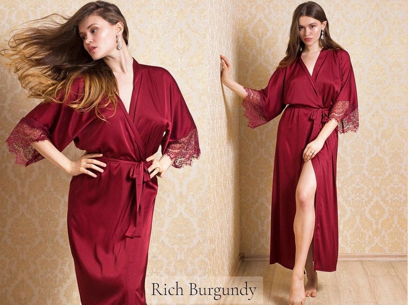 May include: A long, burgundy satin robe with lace trim on the sleeves. The robe has a tie belt and a front slit.