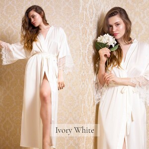 May include: A long white satin robe with lace trim on the sleeves. The robe is tied at the waist with a matching sash. The text "Ivory White" is visible at the bottom of the image.