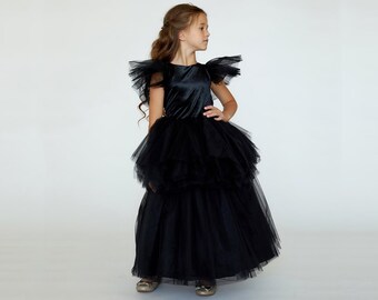 Könnte beinhalten: Ein schwarzes Samt- und Tüllkleid mit Rüschenärmeln. Das Kleid hat ein tailliertes Oberteil und einen weiten Rock.