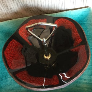 May include: A vintage serving dish with a black and red floral design. The dish has a chrome handle and is divided into five sections. The red sections have a textured appearance, and the dish is set against a teal background.