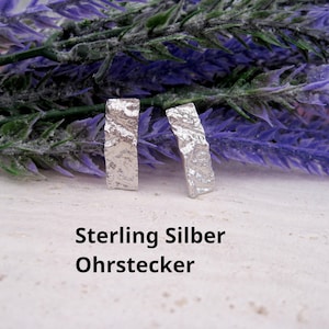 Könnte beinhalten: Ein Paar rechteckige Ohrstecker aus Sterlingsilber mit einer texturierten, unebenen Oberfläche. Die Ohrstecker sind aufrecht positioniert und der Text "Sterling Silber Ohrstecker" ist in Schwarz auf der Fläche darunter aufgedruckt.