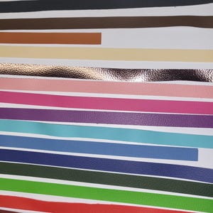 K&ouml;nnte beinhalten: Eine Auswahl an Lederstreifen in verschiedenen Farben, darunter Schwarz, Braun, Beige, Rosa, Lila, T&uuml;rkis, Blau, Dunkelblau, Gr&uuml;n, Rot und Weinrot. Die Streifen sind in Reihen auf einer wei&szlig;en Oberfl&auml;che angeordnet. gghobbyhorses steht oben im Bild.