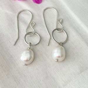 Freshwater Pearl and sterling silver drop earrings. Earrings are approximately 4cm in length, the pearls are approximately 15mm in length and dangle from a jump ring that has an ear wire attached