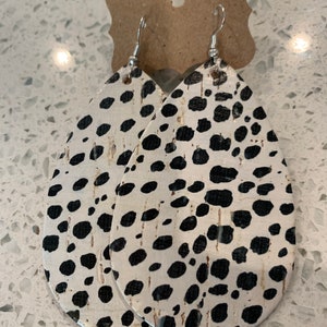May include: A pair of white and black dalmatian print cork earrings with silver hooks.