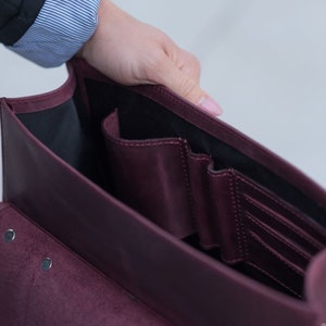 May include: A burgundy leather briefcase with multiple interior pockets and a flap closure.