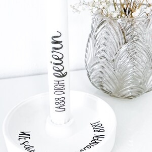 May include: White ceramic holder with the text "Wie sch&ouml;n, dass du bist" and "Lass dich feiern" on the side. The holder is holding a white cylinder with the text "Lass dich feiern" on it.