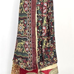 Può includere: Una lunga gonna avvolgente multicolore con stampa paisley. La gonna è realizzata in un tessuto morbido e fluido e ha una chiusura a nodo in vita. La gonna è esposta su un manichino nero.