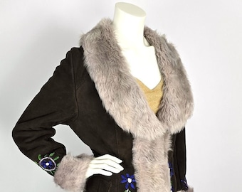 May include: A dark brown suede coat with a faux fur collar and cuffs. The coat features blue floral embroidery along the front and sleeves. The coat is displayed on a mannequin.