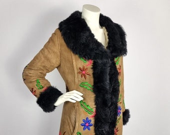May include: A long brown suede coat with a black shearling collar and cuffs. The coat is embroidered with colourful flowers and leaves.