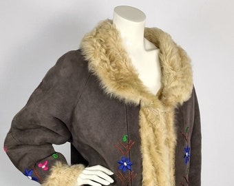 May include: A brown sheepskin coat with a fur collar and cuffs. The coat is embroidered with colourful flowers and vines.