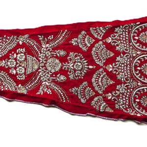 Può includere: Una lunga striscia di tessuto rosso con ricami argentati intricati. Il design presenta motivi floreali e forme geometriche ripetuti.