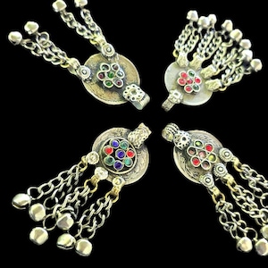 May include: Four silver-toned metal pendants featuring circular centers with embedded red, green, and blue stones. Each pendant has multiple dangling chains ending in small metal beads, creating a layered, articulated design with intricate metalwork.