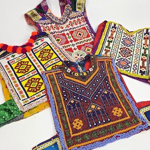 May include: Five colourful embroidered fabric panels with intricate beading and geometric patterns. The panels are made of a variety of fabrics, including velvet, silk, and cotton. The colours are vibrant and include red, blue, yellow, green, and white.