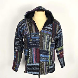 May include: A hooded jacket with a patchwork design. The jacket features a black hood and a full-length zipper. The patchwork design incorporates various colors, including blue, green, red, and white, creating a unique and textured appearance. The jacket is displayed on a mannequin.