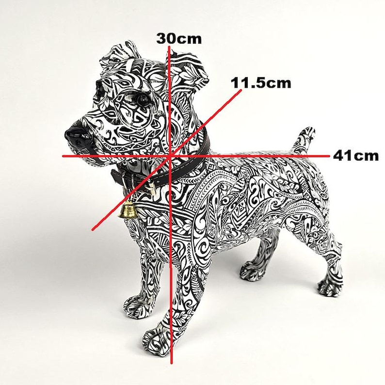 May include: A black and white decorative dog statue with intricate patterns. The statue measures 16 inches long, 12 inches high, and 4.5 inches wide. It features a black collar with a gold bell.