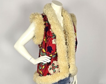 Puede incluir: Un chaleco sin mangas con un estampado floral rojo y un cuello y ribete de piel sintética de color crema.
