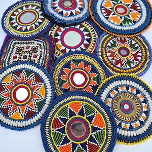 May include: A collection of colorful, beaded coasters with intricate patterns. Each coaster features a central mirror and is adorned with vibrant beads in shades of blue, orange, yellow, and white. The designs vary, showcasing geometric and floral motifs.