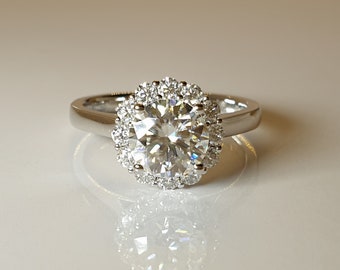 May include: A silver ring with a large, round, clear diamond center stone surrounded by a halo of smaller diamonds.