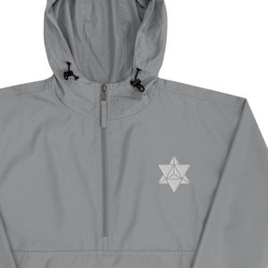 Puede incluir: Una chaqueta cortavientos gris con capucha, cierre de cremallera y un logotipo de estrella geométrica blanca en la parte delantera. La chaqueta tiene capucha con cordón y puños elásticos.