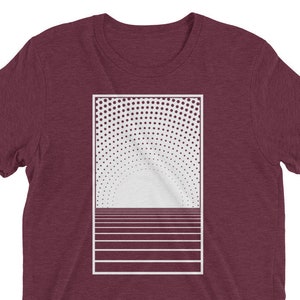 Puede incluir: Una camiseta color granate con un diseño gráfico blanco de una puesta de sol estilizada con un sol punteado y líneas horizontales.