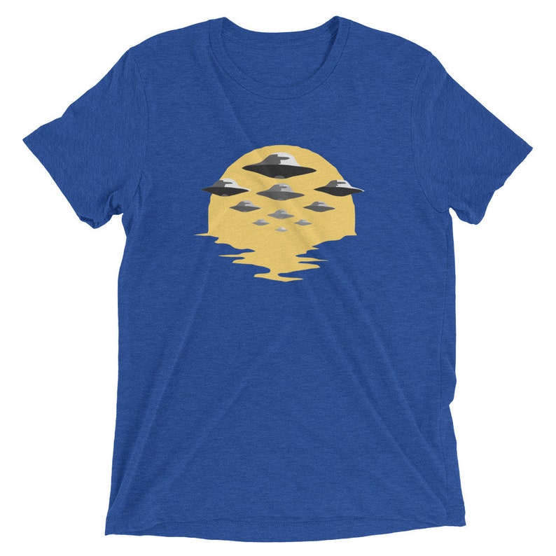 Puede incluir: Una camiseta azul real con un gr&aacute;fico de un sol amarillo con varios OVNIs grises volando sobre &eacute;l.