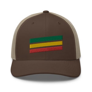 Puede incluir: Una gorra de camionero marr&oacute;n y beige con un dise&ntilde;o de rayas verdes, amarillas y rojas en la parte delantera.
