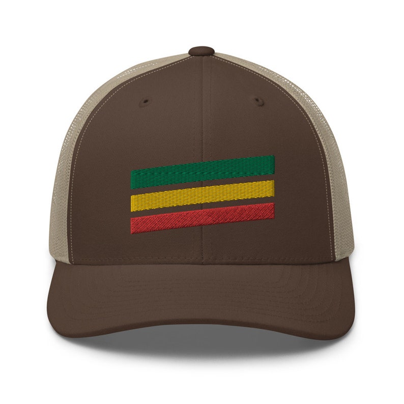 Puede incluir: Una gorra de camionero marr&oacute;n y beige con un dise&ntilde;o de rayas verdes, amarillas y rojas en la parte delantera.