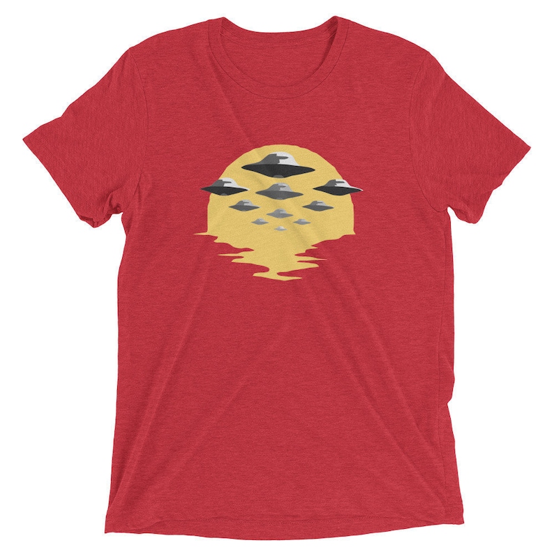 Puede incluir: Camiseta roja con un gr&aacute;fico de un sol amarillo y m&uacute;ltiples platillos voladores en formaci&oacute;n.