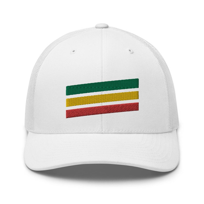 Puede incluir: Gorra de camionero blanca con un dise&ntilde;o de rayas verdes, amarillas y rojas bordado en la parte delantera.