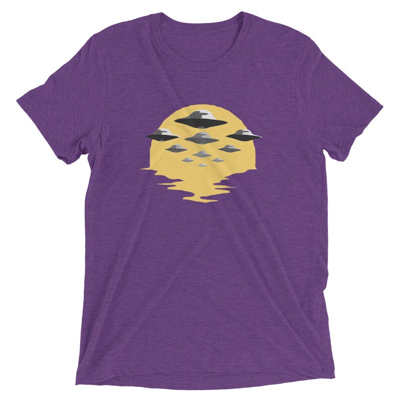 Puede incluir: Camiseta morada con un gr&aacute;fico de un sol amarillo con m&uacute;ltiples platillos voladores delante.