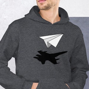May include: A dark gray hooded sweatshirt with a white paper airplane flying over a black silhouette of a jet fighter.