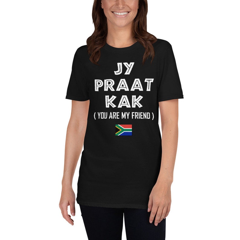 May include: Black t-shirt with white text that reads "Jy Praat Kak (You Are My Friend)" and a South African flag.