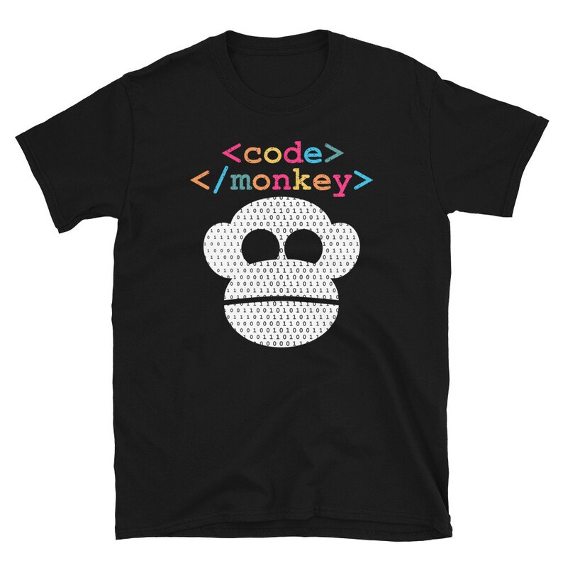 Może przedstawiać: Czarny T-shirt z białą twarzą małpy wykonaną z kodu binarnego. Tekst "<code>/monkey>" jest nadrukowany w kolorach tęczy nad małpą.