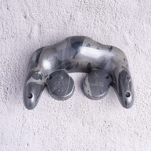 May include: A white ceramic mug with a black handle and the text "But First, Coffee" in a bold, black font. The mug is set against a blurred background, suggesting a cozy setting.