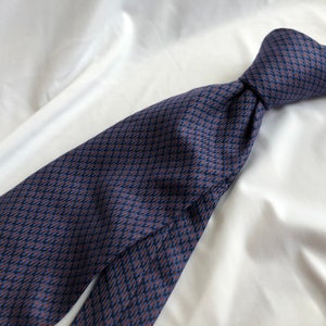 May include: A blue and brown patterned silk tie. The tie has a geometric pattern and is made of a smooth, luxurious fabric.