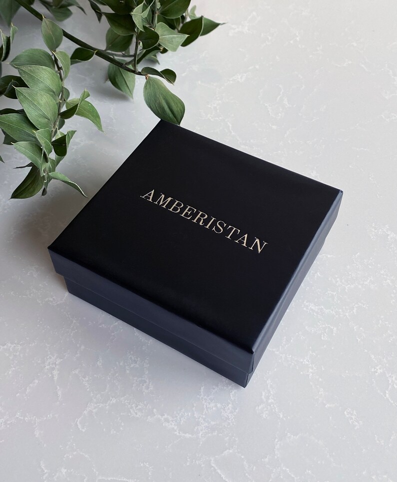 May include: A black square box with the word "AMBERISTAN" printed in gold lettering.