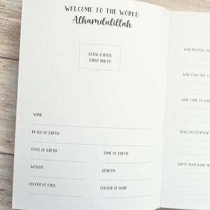 Pode incluir: Um livro branco de mem&oacute;rias de beb&ecirc; com as palavras "Bem-vindo ao mundo Alhamdulillah" e um espa&ccedil;o para colar a primeira foto do beb&ecirc;. O livro tem se&ccedil;&otilde;es para registrar o nome do beb&ecirc;, o local e a data de nascimento, a hora do nascimento, o peso, o comprimento, a cor dos olhos e a cor do cabelo.