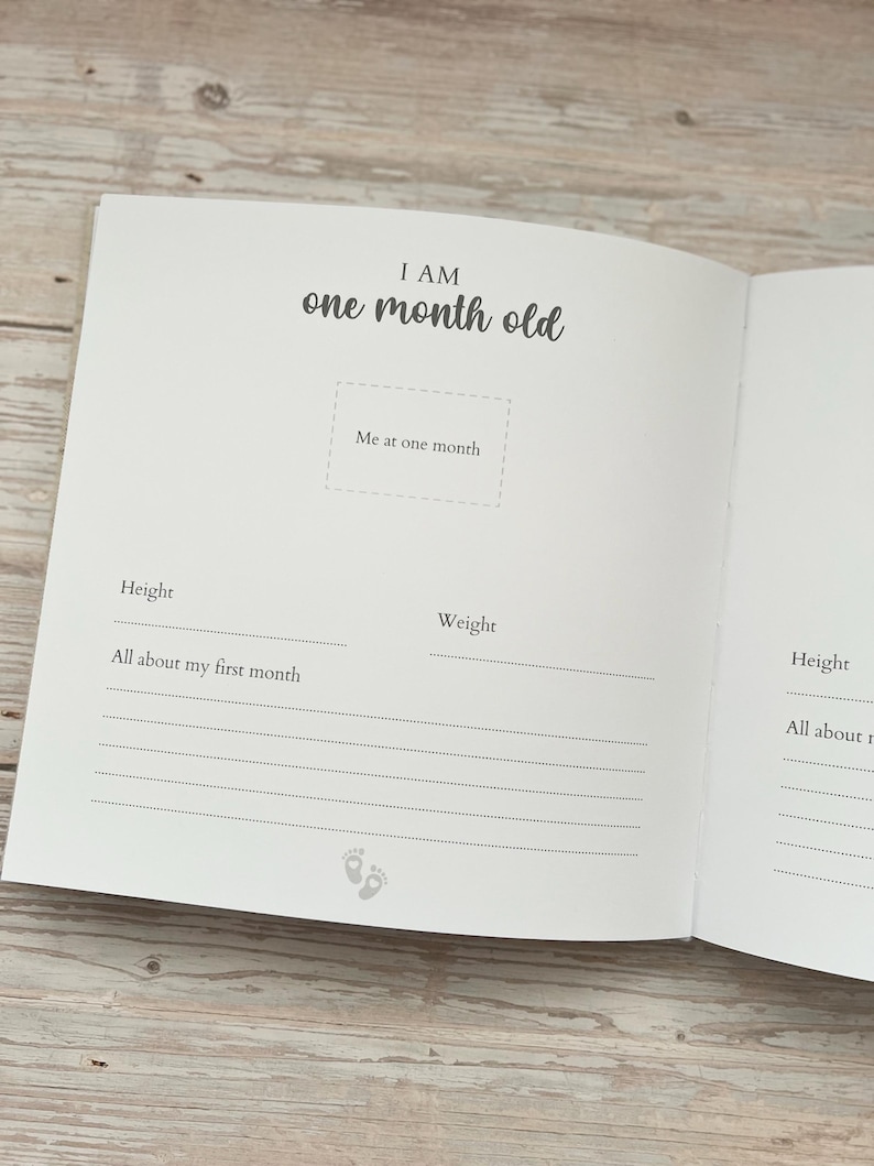 May include: Open baby memory book with the text "I AM one month old." The book has space to record height, weight, and other details. Includes a section for a photo and a line for "All about my first month."