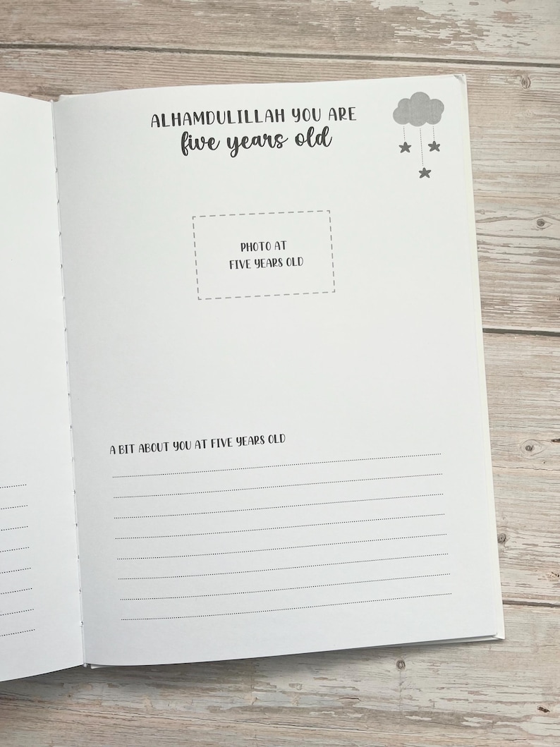 Pode incluir: Um livro branco com um design de nuvem e estrelas em preto e cinza. O texto "ALHAMDULILLAH YOU ARE five years old" est&aacute; impresso na capa. O livro tem um espa&ccedil;o para fotos com o texto "PHOTO AT FIVE YEARS OLD" e uma se&ccedil;&atilde;o para escrever "A BIT ABOUT YOU AT FIVE YEARS OLD".