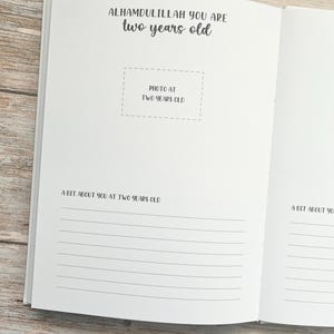 Pode incluir: Um livro branco com o texto "Alhamdulillah you are two years old" e um espa&ccedil;o para uma foto. O livro tem p&aacute;ginas pautadas para escrever sobre o segundo anivers&aacute;rio de uma crian&ccedil;a.