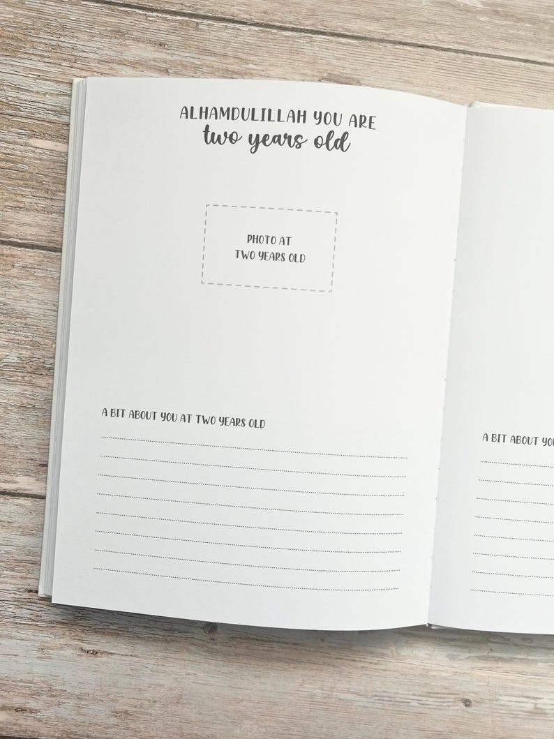 Pode incluir: Um livro branco com o texto "Alhamdulillah you are two years old" e um espa&ccedil;o para uma foto. O livro tem p&aacute;ginas pautadas para escrever sobre o segundo anivers&aacute;rio de uma crian&ccedil;a.