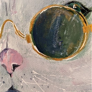 May include: A close-up of a white cat's face with a single round, gold-rimmed eyeglass lens. The lens is green and has a gold rim. The cat's nose is pink and its whiskers are visible.